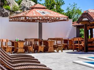 a patio with an umbrella and wooden tables and chairs at Apartment Delfin-7 by Interhome in Cesarica