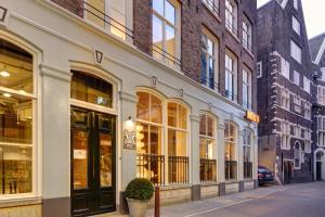 - un bâtiment avec de nombreuses fenêtres donnant sur une rue de la ville dans l'établissement Hotel V Nesplein, à Amsterdam