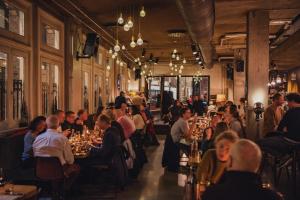 un groupe de personnes assises à table dans un restaurant dans l'établissement Hotel V Nesplein, à Amsterdam