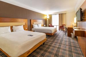 a hotel room with two beds and a desk at Bromsgrove Hotel in Bromsgrove