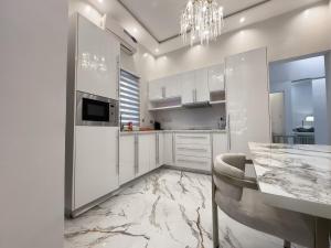 a kitchen with white cabinets and a marble floor at Teflon suites Kumasi in Kumasi
