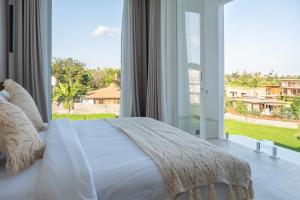 een slaapkamer met een wit bed en een groot raam bij White Palm Villa in Canggu +36 foto's