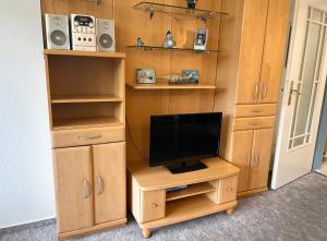 a room with a tv on a stand with a desk with a television at Apartmenthaus Frauenpreiss FeWo 303 in Cuxhaven