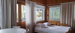 a bedroom with two beds and a table and two windows at Miiluranta Villas in Haapamäki