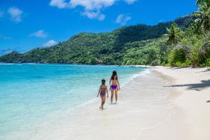 dos chicas caminando por la playa en Chalets d'Anse Forbans SelfCatering, en Takamaka