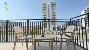 a balcony with three chairs and a table and a building at Rodeo Retreat - Chic 1BR Apartment on Yas Island, 12 Min to Grand Prix in Abu Dhabi
