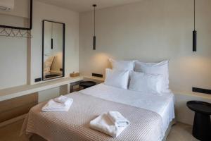 a bedroom with a white bed with two towels on it at Stone Villas in Skiathos Town +65 photos