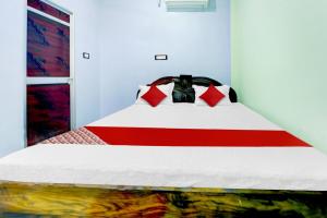 a bedroom with a bed with a red and white comforter at Hotel O Laxmi Marriage Hall Restaurant And Guest House in Islāmpur +27 photos
