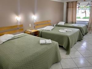 a hotel room with two beds with green blankets at Hotel San Bernardino in Guaramirim
