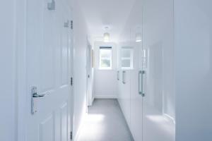 a white bathroom with white doors and a hallway at Grange House in Chester +44 photos
