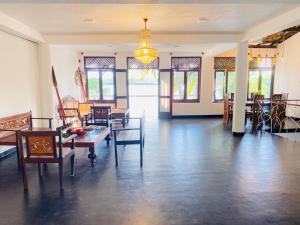 a living room with tables and chairs and a chandelier at Lake Duwa Hotel in Ambalangoda