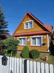 a yellow house with a white fence in front of it at Dom Słoneczko pokoje do wynajęcia w Białowieży in Białowieża