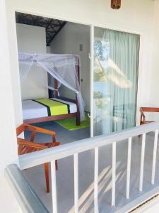 a room with a balcony with a bed and a window at Lake Duwa Hotel in Ambalangoda