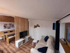 a living room with a white couch and a television at Ferienwohnung Goasnstoi - mit HotTub und Bergblick im Inntal in Flintsbach am Inn
