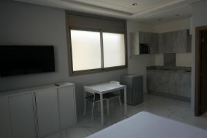 a room with a television and a table and a window at Les portes de Temara in Temara