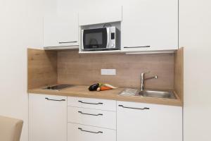 a kitchen with white cabinets and a sink and a microwave at OVELIA Angers - Les Jardins d'Arborescence in Angers +4 photos