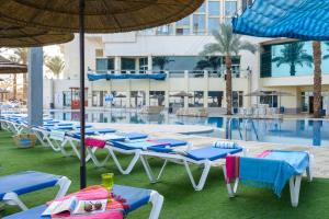 un grupo de sillas y sombrillas junto a una piscina en Leonardo Plaza Hotel Dead Sea en Ein Bokek