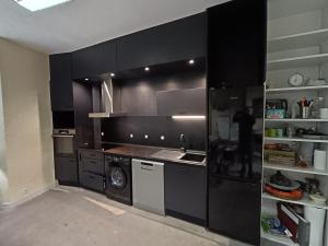 Una cocina con gabinetes negros y un fregadero. en Maison de la cité des 3 vallées, en Saint-Brieuc
