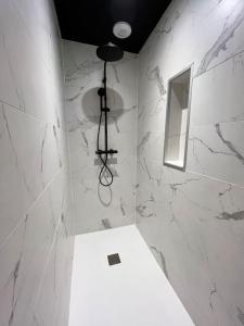 a bathroom with a shower with white marble walls at Emeraude vue mer MALO LES BAINS in Dunkerque