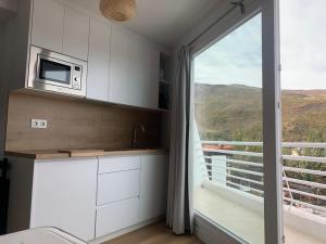 kuchnia z kuchenką mikrofalową i dużym oknem w obiekcie Apartamento Plaza Pradollano 2 w mieście Sierra Nevada