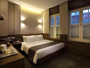 a bedroom with a large bed and two windows at Arcadia Hotel in Singapore