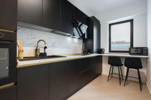 a kitchen with black cabinets and a sink and two chairs at Skyline Black - Cortina North in Voluntari