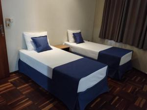 two beds with blue and white sheets in a room at Pouso Alegre Hotel INN - Próximo a Unimed e Rodoviária in Pouso Alegre