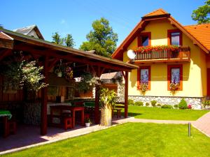 una casa amarilla con una mesa y sillas en un patio en Penzion Bado, en Stará Lesná