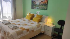 a bedroom with a bed with yellow pillows and a chair at Pensión Mar Azul in Santiago de Compostela