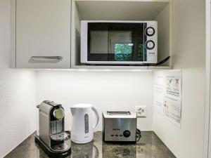 Apartment Chalet Colette-2 by Interhome في جريندلفالد: طاولة مطبخ مع ميكروويف وآلة صنع قهوة