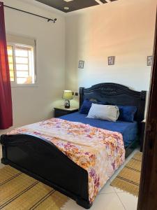 a bedroom with a bed with a blue comforter and a window at Modern Moroccan apartment near the beach in Safi in Safi