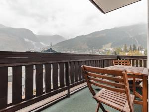 een houten tafel en stoelen op een balkon met uitzicht op de bergen bij Apartment Landhaus St- Georg-3 by Interhome in Bad Gastein
