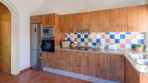 a kitchen with wooden cabinets and a stainless steel refrigerator at Villa Manolo Torrox by Ruralidays in Torrox