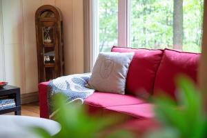 a red couch with a pillow on it in a living room at View and access to Lake Orford - Spa - Australe in Austin