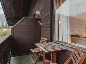 een houten tafel en 2 stoelen op een balkon bij Apartment Landhaus St- Georg-7 by Interhome in Bad Gastein