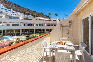 Un patio con mesa y sillas y un edificio. en Central Los Gigantes Florida By Dreamhomestenerife, en Acantilado de los Gigantes