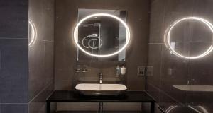 a bathroom with a sink and two round mirrors at The Bold Hotel; BW Signature Collection in Southport