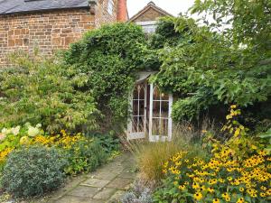 a garden with flowers and a building with a window at Charming Old Schoolroom in Daventry