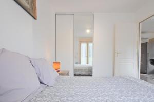 a white bedroom with a bed and a mirror at Chalet avec piscine privée in Savignac-les-Églises +16 photos