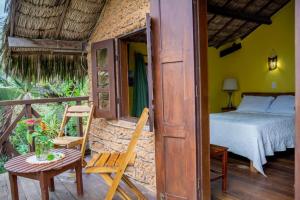 a bedroom with a bed and a table and a chair at Pousada Chale Creoulo in Jericoacoara