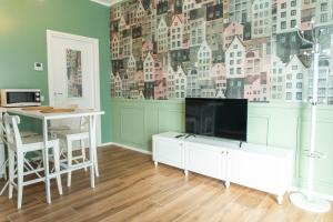 a living room with a tv and a desk and a table at Moderno Bilocale con Aria Condizionata vicino a Duomo, Fondazione Prada e IEO in Milan