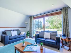 a living room with two blue couches and a table at Chalet Caledonia Lodge by Interhome in Spean Bridge