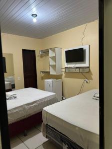 a room with two beds and a tv on the wall at Hotel Asa Branca in Boa Vista