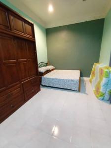 a bedroom with two beds and a wooden cabinet at Zafhomestay Kuala Terengganu in Kampong Batu Burok +4 photos