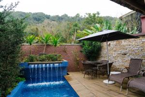 a swimming pool with an umbrella and a table and chairs at Casa Formosa Baleia in São Sebastião
