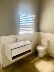 a bathroom with a white sink and a toilet at 114 Zinnia in Midrand +4 photos