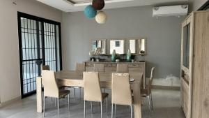 una sala da pranzo con tavolo e sedie in legno di VILLA AVEC PISCINE à NGAPAROU à 1 MIN DE LA PLAGE A PIED a Ngaparou