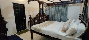 a bedroom with a wooden bed with white sheets and pillows at PADIKKAL BUNGLOW in Vayittiri +28 photos