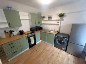 a kitchen with green cabinets and a washing machine at The Pink House in Torquay