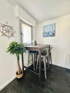 a dining room with a table and chairs and a plant at Un été sans fin à Deauville in Deauville